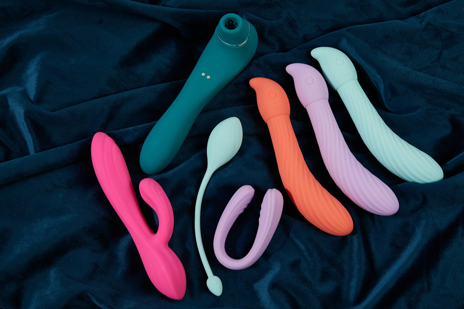 Colorful silicone vibrators and adult toys on dark fabric