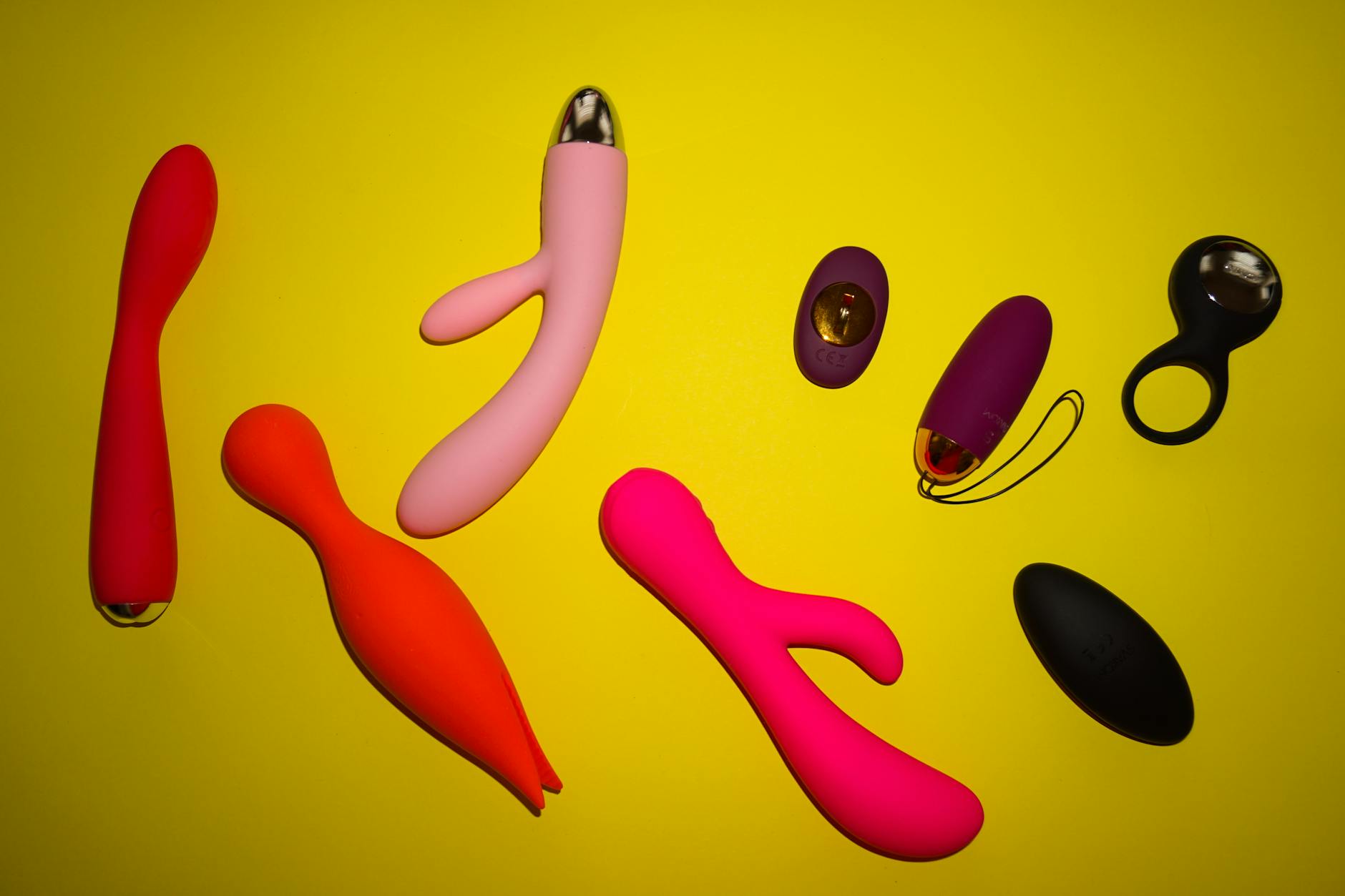 Blue vibrator surrounded by flowers and citrus on a yellow background