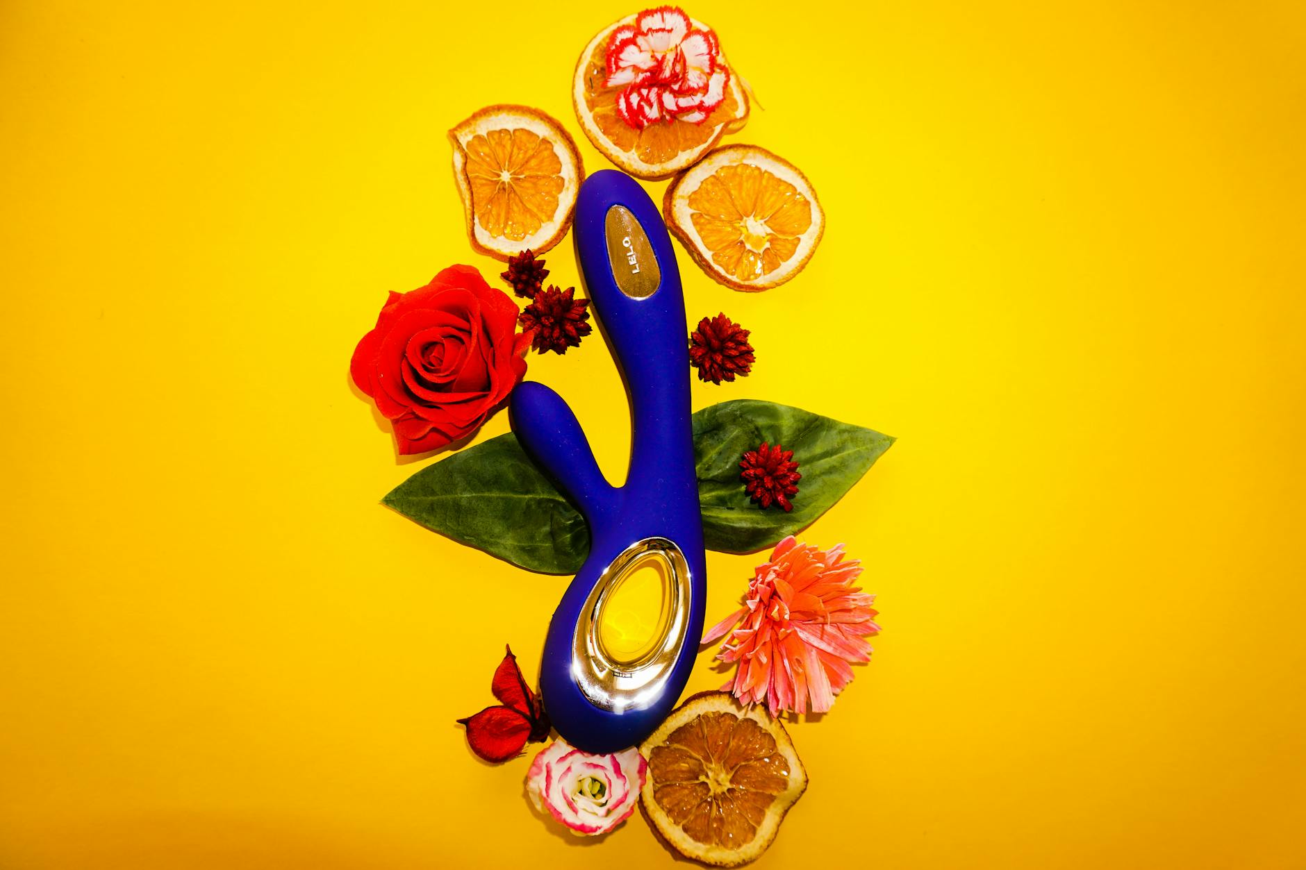 Close-up of a hand holding a lemon vibrator against a purple backdrop, representing modern couples sensuality
