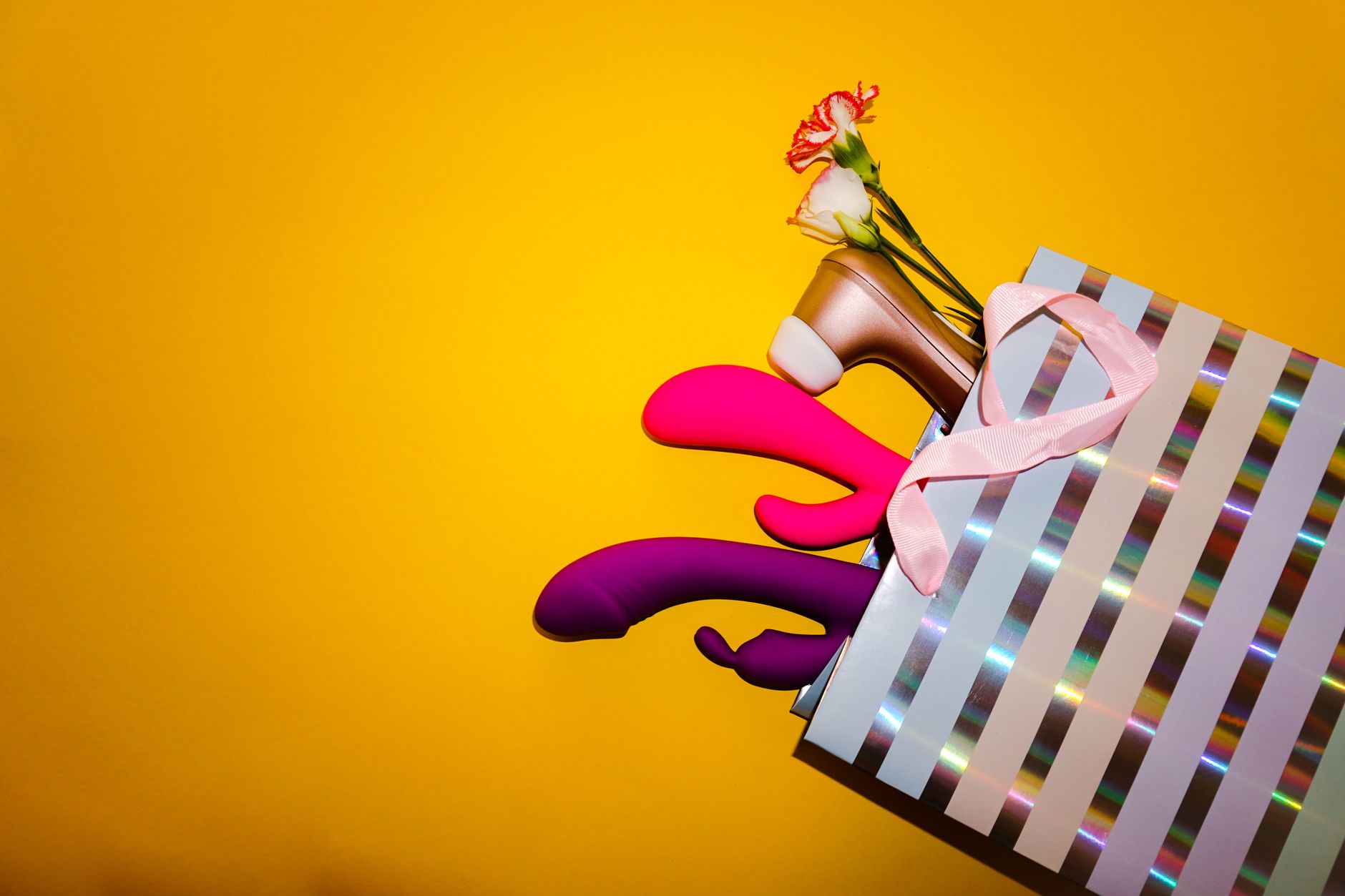Woman holding colorful vibrators in a contemplative pose, exploring pleasure and sensation
