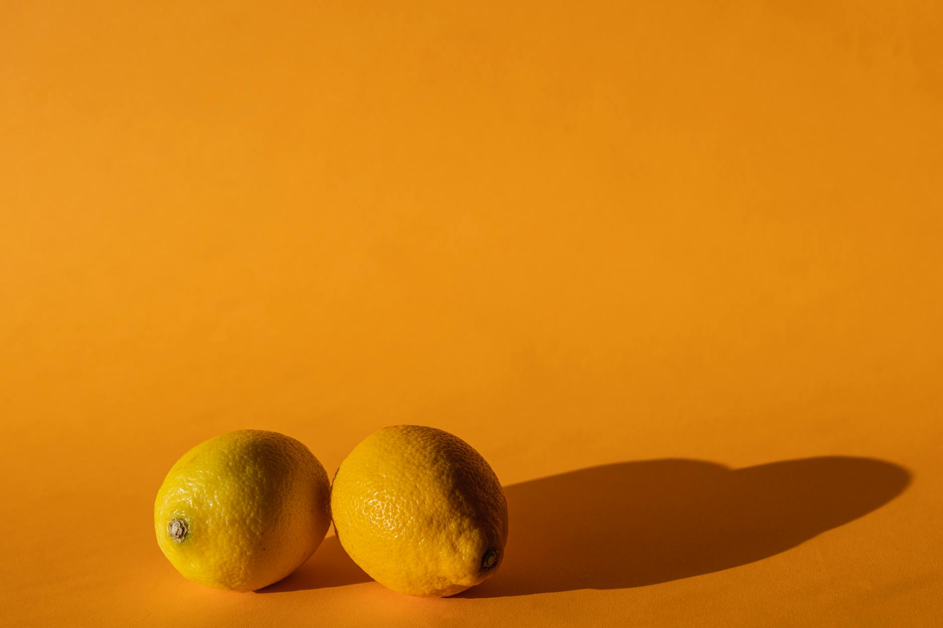 A creative composition featuring a hand holding a lemon against a vivid yellow background, conveying a fresh and citrusy vibe.